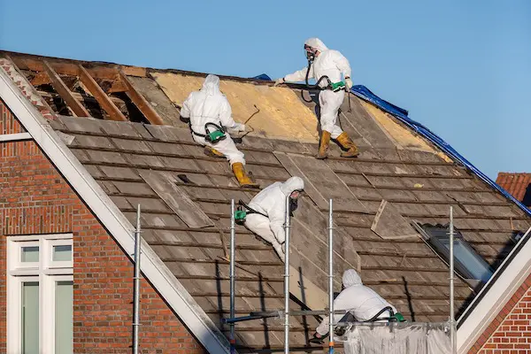 Construction workers are wearing PPE and removing asbestos materials.