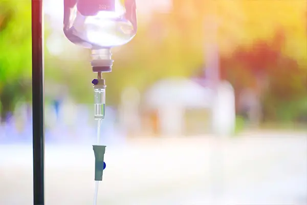 A bag of mesothelioma immunotherapy drugs hangs from an IV stand in front of a window.